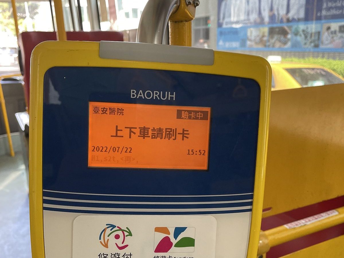 公車車內的黃色電子票證讀卡機，螢幕顯示上下車請刷卡