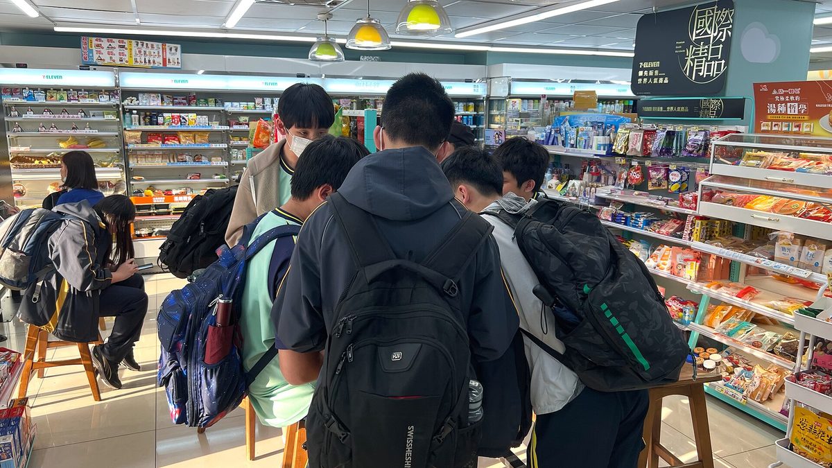 數名背書包的學生在便利商店內選購商品